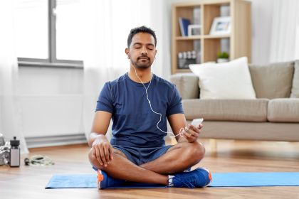 /sport-technology-and-healthy-lifestyle-concept-indian-man-in-earphones-listening-to-music-on-smartphone-at-home