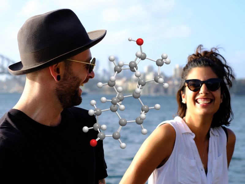 Man and woman sharing a joke with a chemical symbol of male and female testosterone floating between them