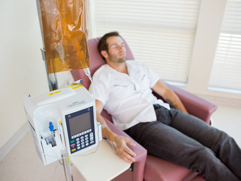 Man reclining near an IV drip to illustrating receiving NAD+ therapy