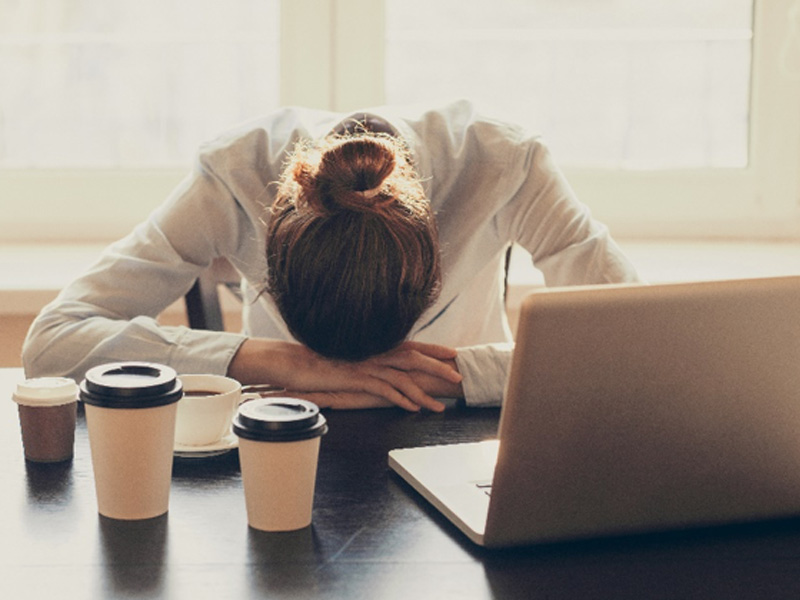 Female head down over desk to illustrate exhaustion and the need for adrenal fatigue treatment