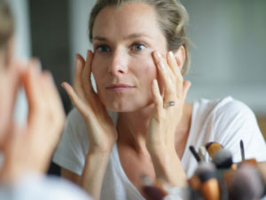 woman looking in mirror to illustrate microdermabrasion facial
