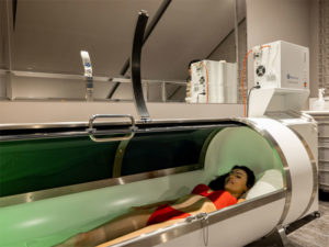 woman lying in oxygen capsule to illustrate hyperbaric oxygen therapy