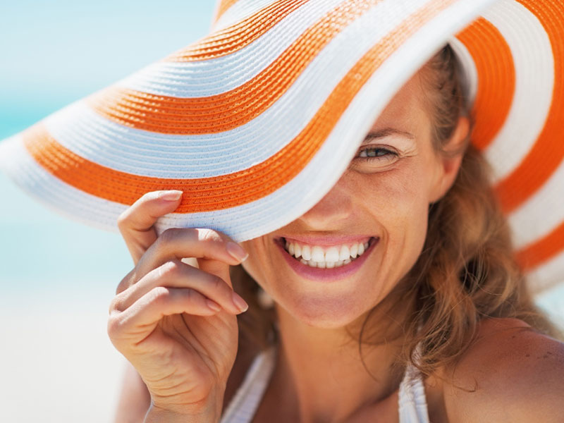 young woman in swimsuit and beach hat to illustrate safe aesthetic procedures for summer