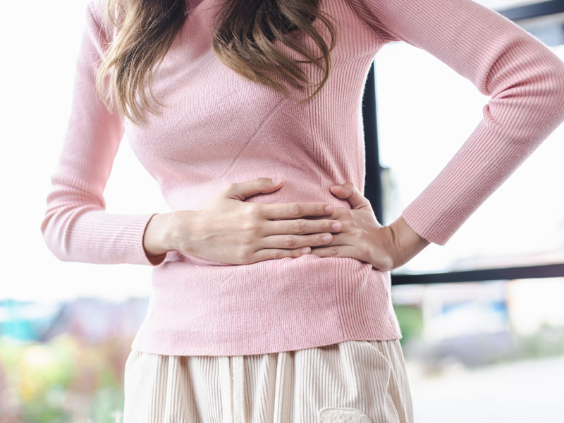 woman holding her stomach to illustrate the need for good gut health