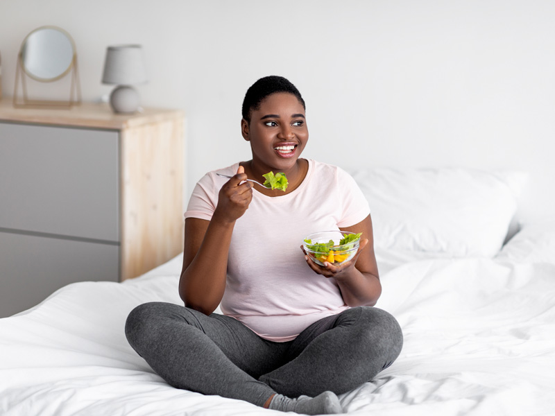 Woman on bed eating a healthy snack to illustrate good nutrition helping with using weight loss medication