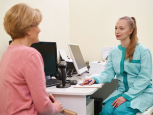 young doctor talking with older woman to illustrate discussing hormonal imbalance after hysterectomy