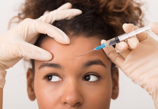 African american women gets an injection of dysport in her forehead