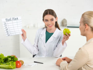 smiling dietician holding a weight plan card to show the role of functional nutrition in a weight loss program