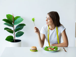 young woman eating a salad and contemplating being thinner after semaglutide help