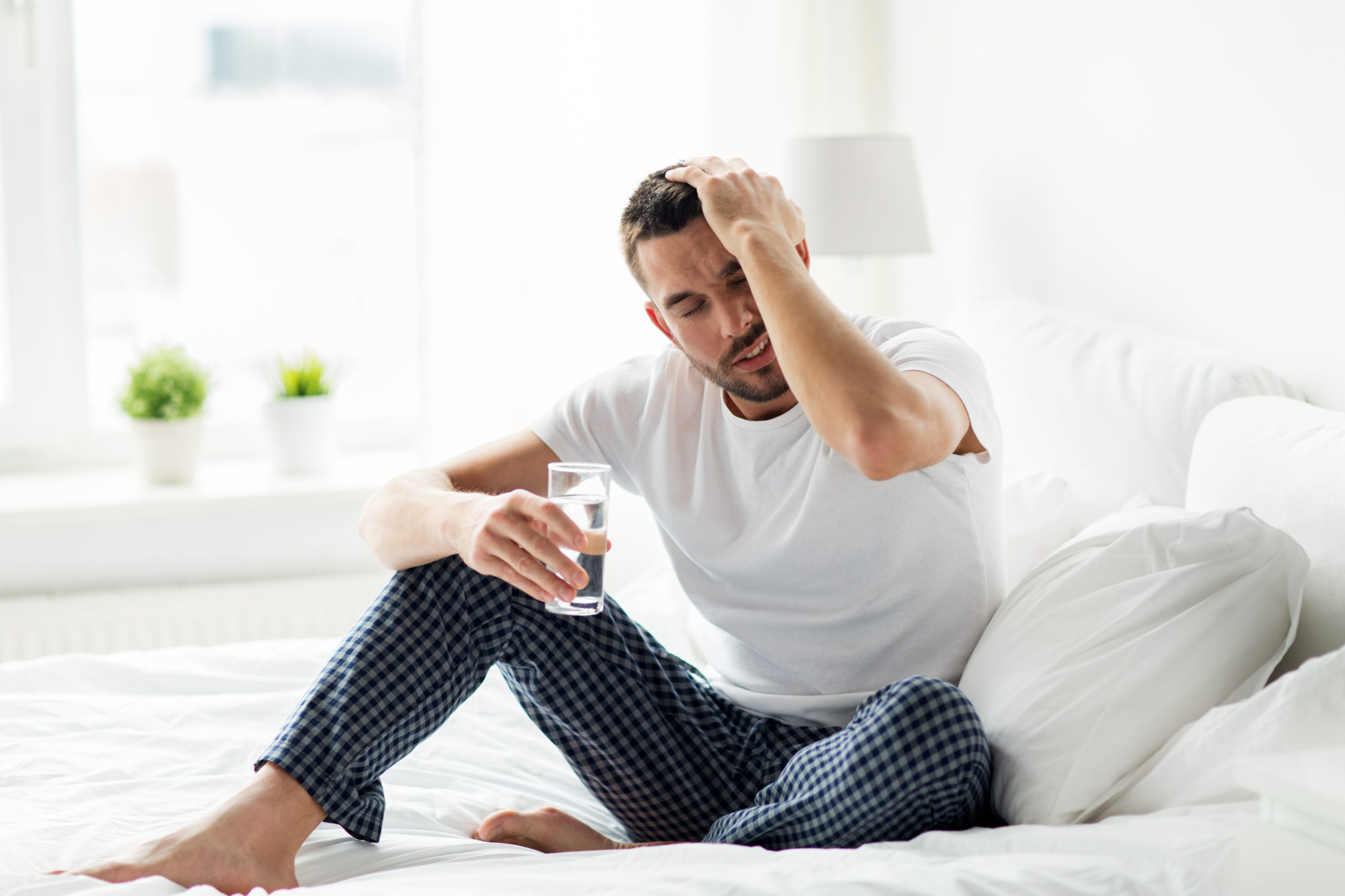 man in bed with glass of water at home