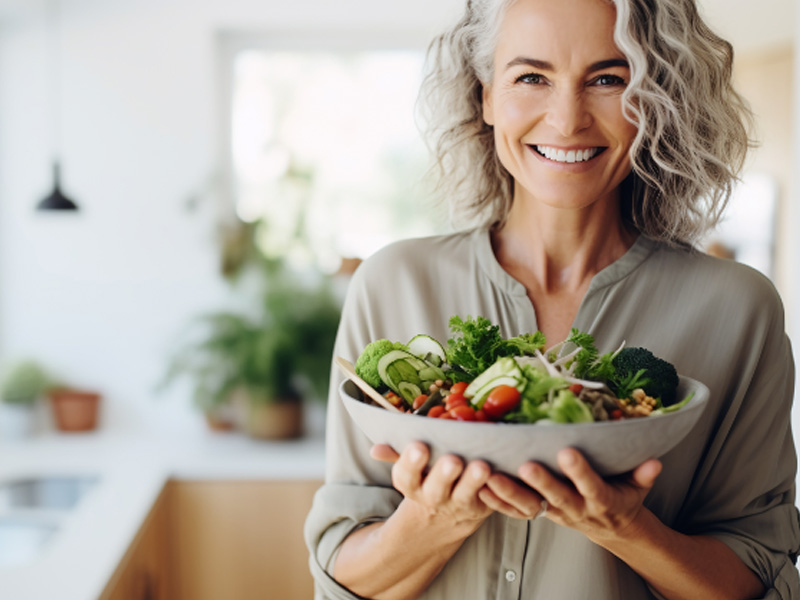 woman holding a dish of healthy food to illustrate a perimenopause diet