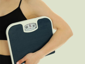 sporty woman carrying scales to illustrate managing her weight with a perimenopause diet