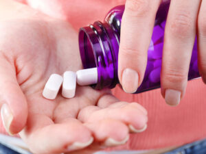 bottle of tablets falling into a hand to illustrate choosing a calcium and magnesium supplement
