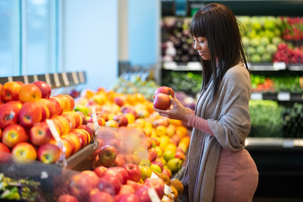 African American woman shopping for produce in grocery store and following a healthy diet for long term weight loss