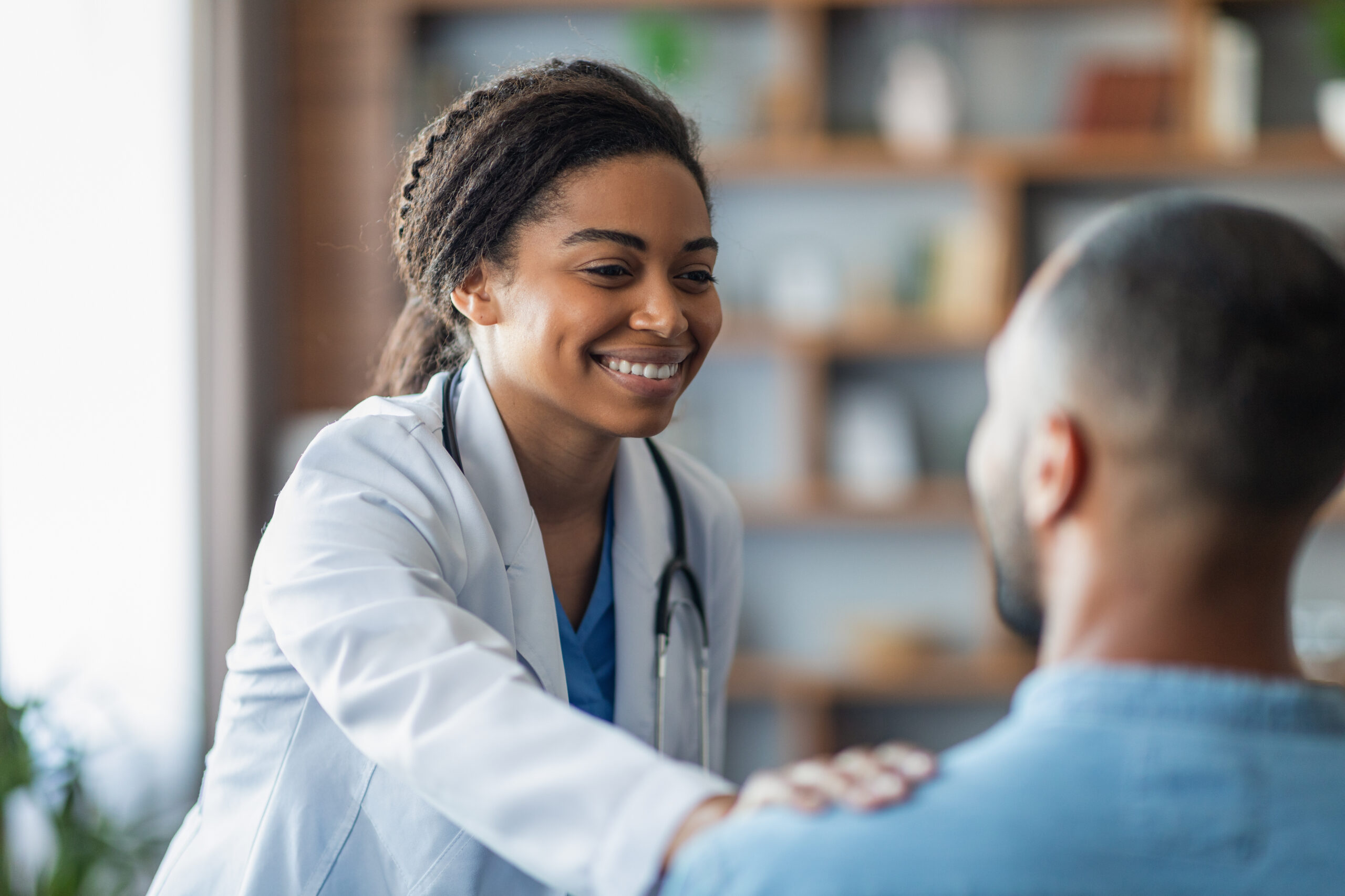 Cheerful attractive young african american woman doctor touching unrecognizable eastern man patient shoulder, general practitioner happy with results of treatment, supporting her patient, closeup