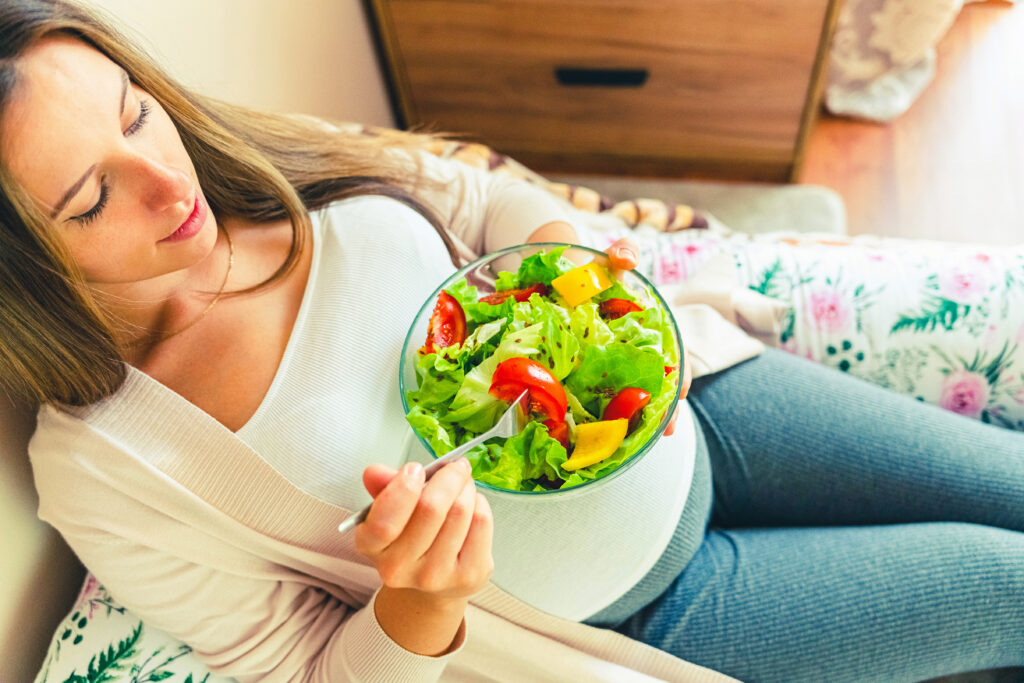 Pregnancy eating healthy salad. Happy pregnant woman eating nutrition food. People lifestyle food concept.