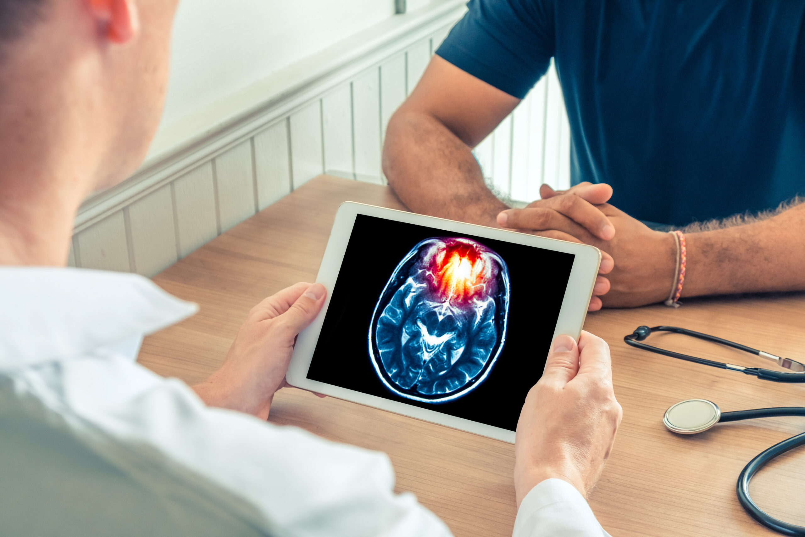 Doctor holding a digital tablet with a brain scan of the patient.