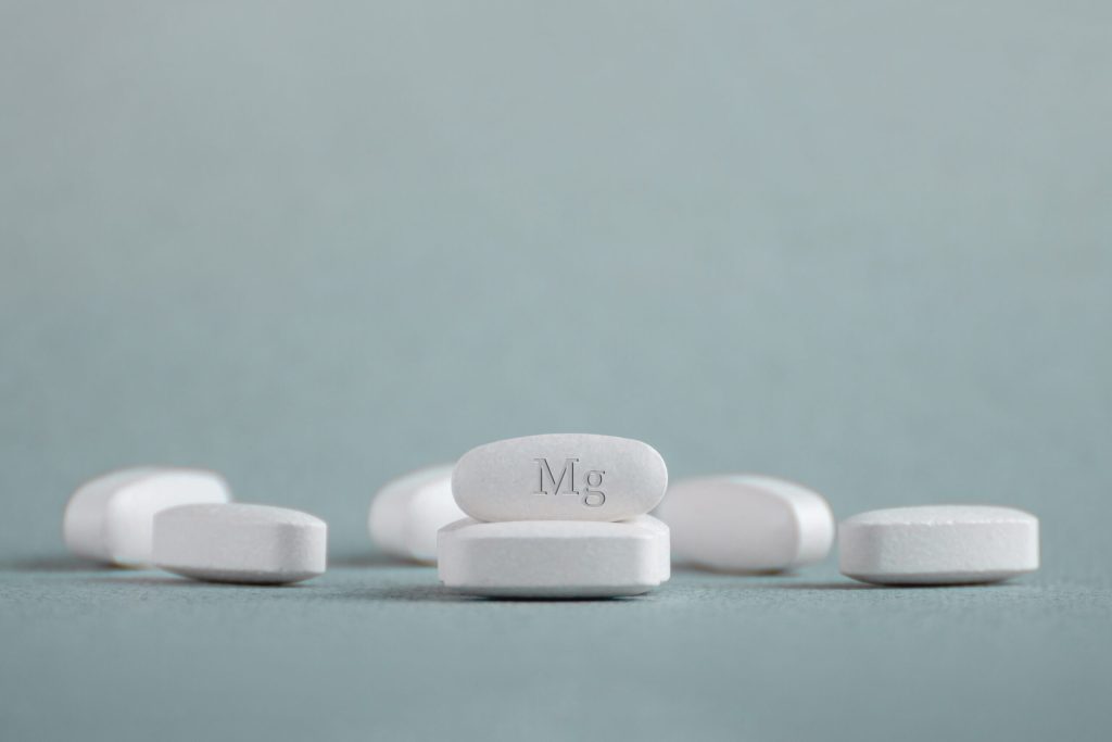Tablets , vitamins with the abbreviation Mg ( magnesia, macro element magnesium ) on a light background.