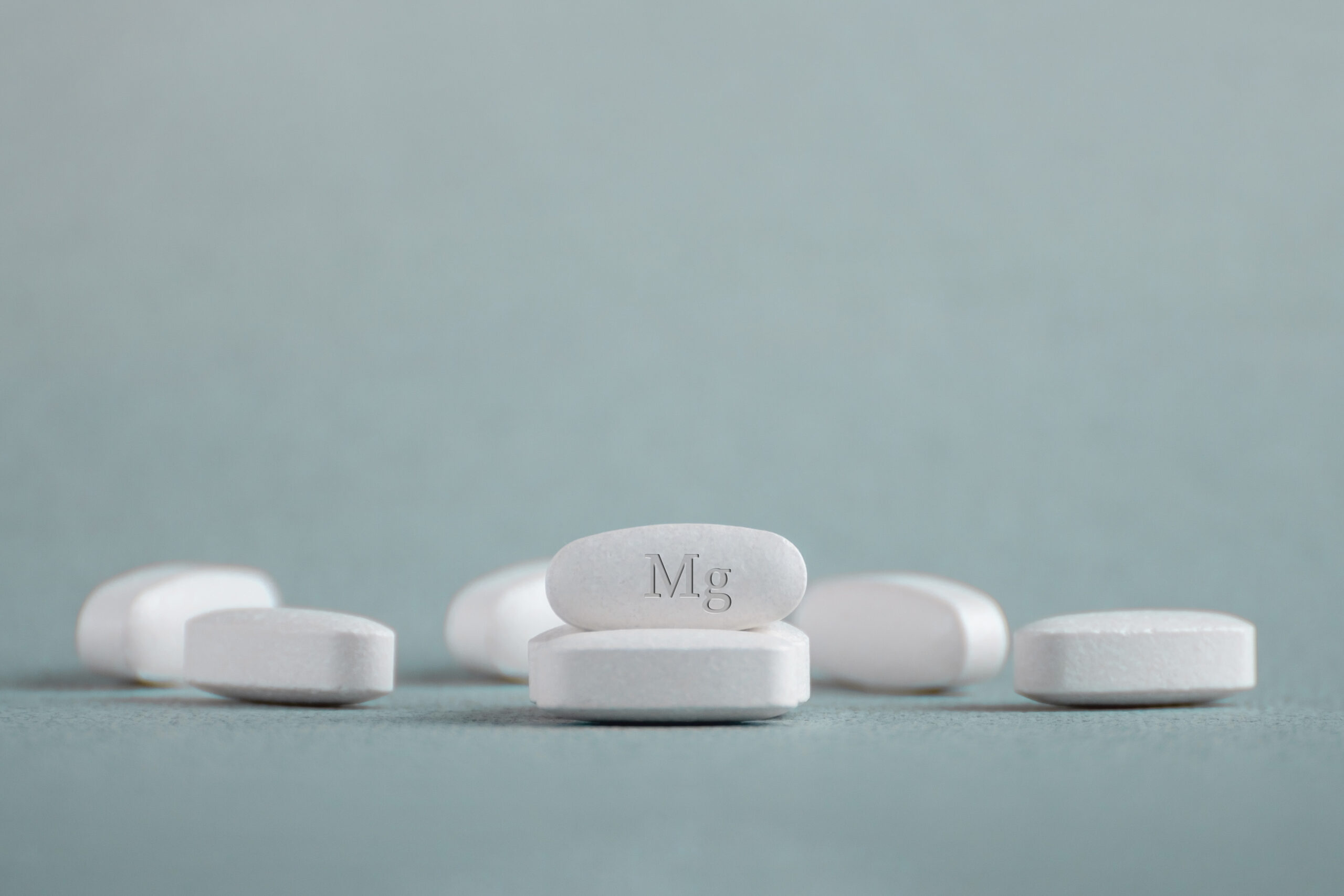 Tablets , vitamins with the abbreviation Mg ( magnesia, macro element magnesium ) on a light background.