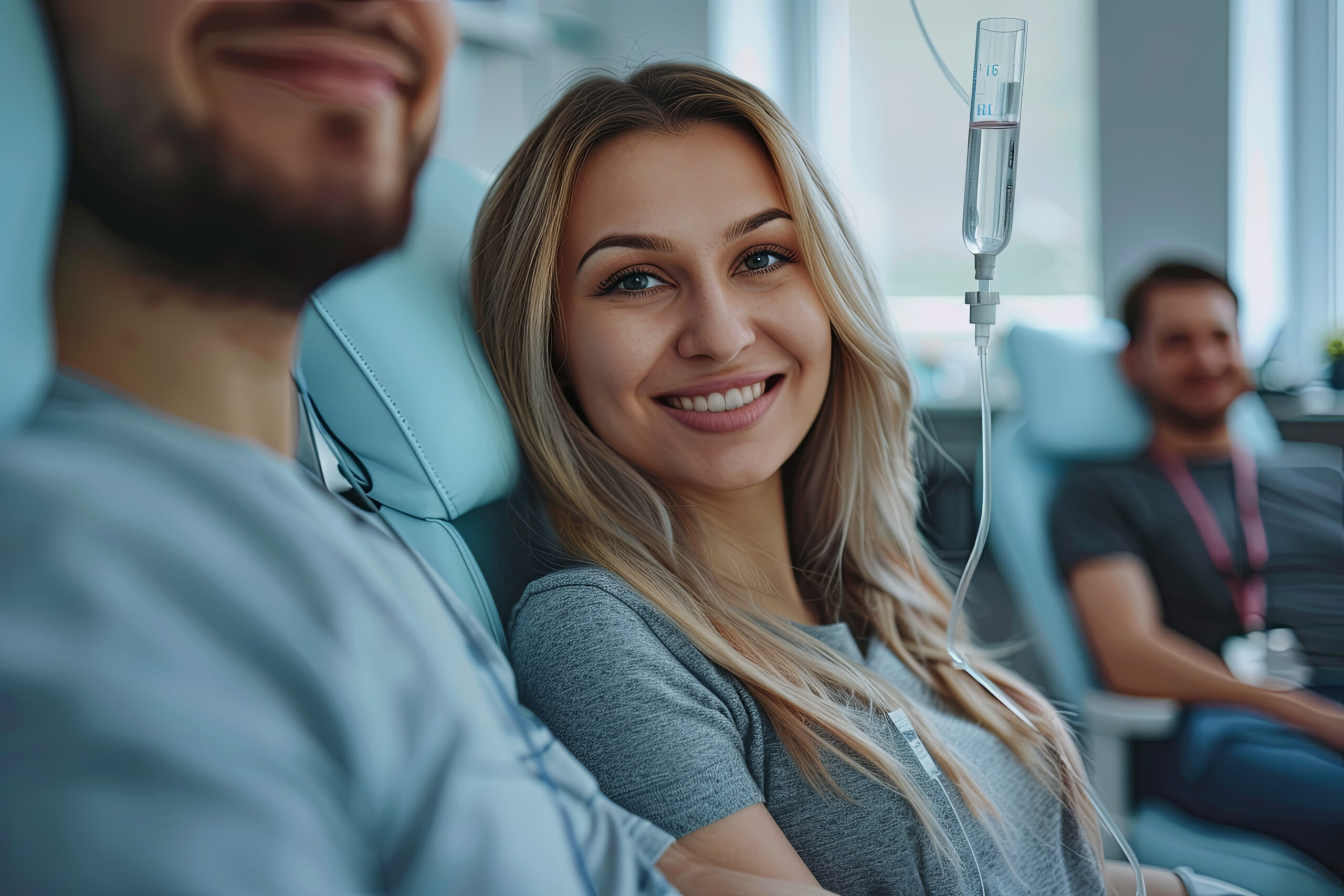 Maintenance and restoration of human immune system with vitamin IV infusion therapy. Beautiful woman with her boyfriend in modern wellness center during intravenous vitamin therapy