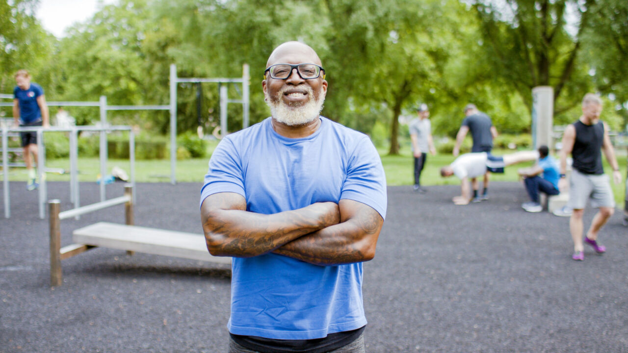 Portrait of confident, muscular black senior man with his arms folded smiling to camera