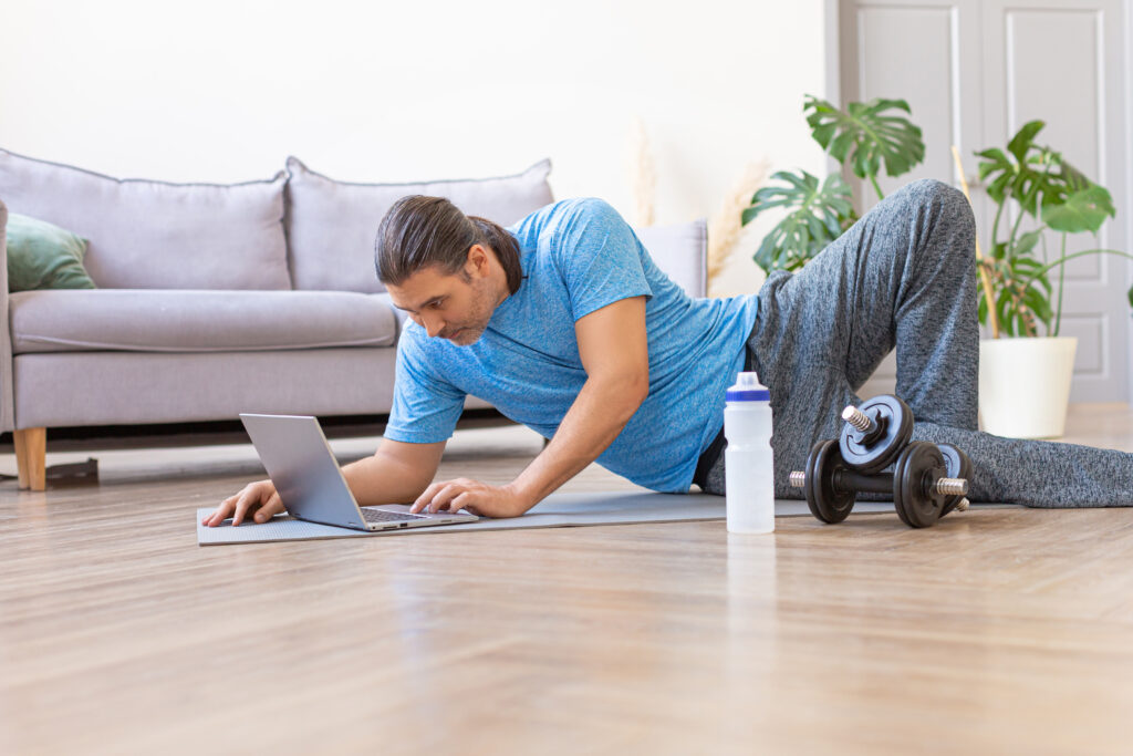 Photo of a man looking for exercise routines online. Home online workout.