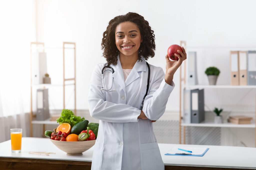 Pretty black lady clinical nutritionist holding apple in her hand