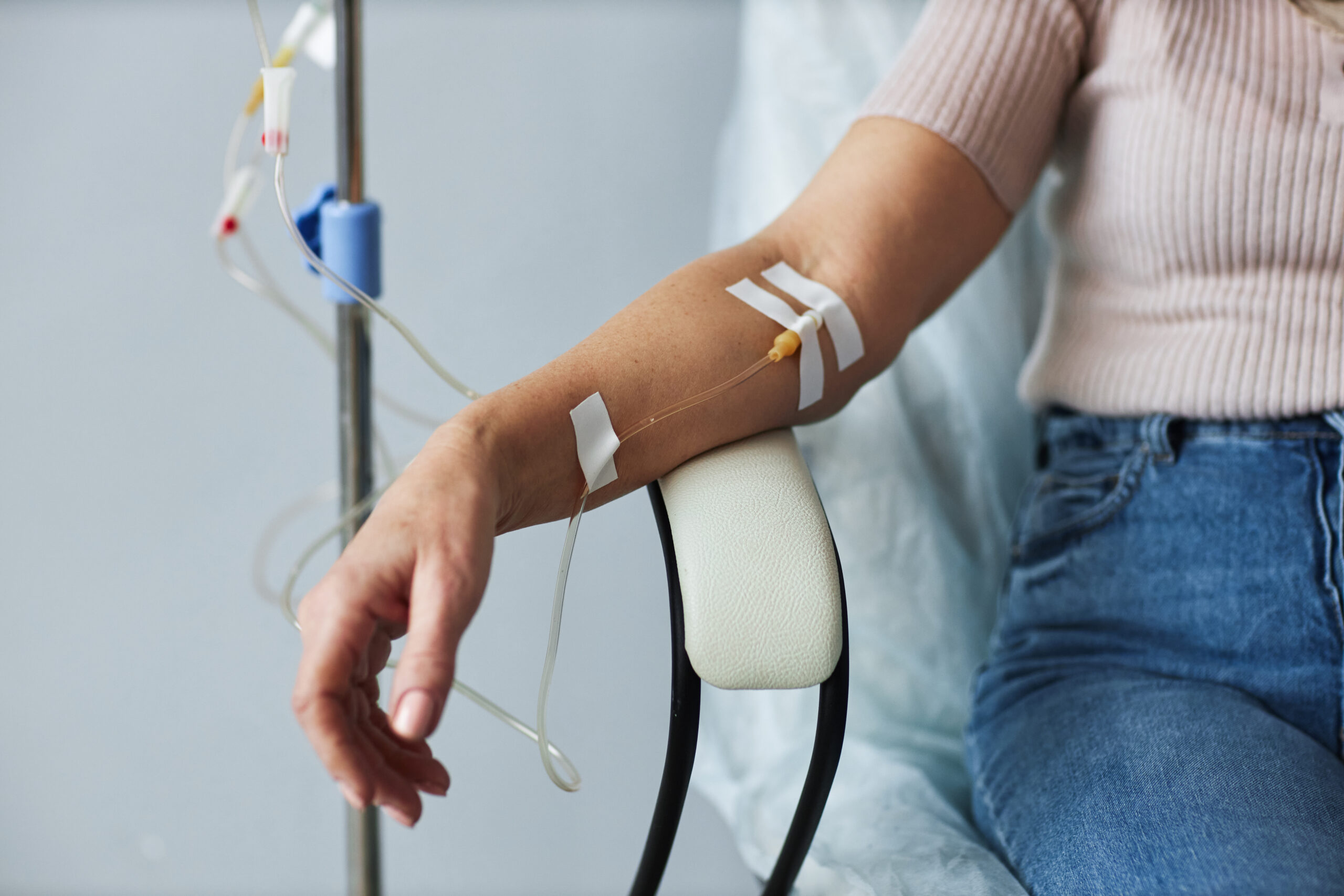 Licensed Closeup of female hand with IV drip infusion in treatment session at hospital, copy space